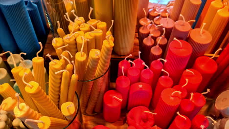 una exhibición colorida de velas variadas en varias formas y tamaños en una mesa de madera