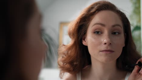 caucasian woman applying eyelash in the mirror reflection.
