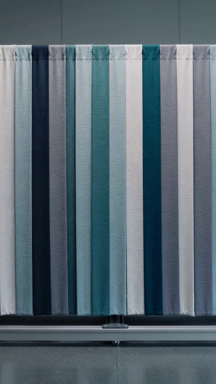 Vertical video: Sliding striped curtain moving right on metal track at gallery, showing teal panels