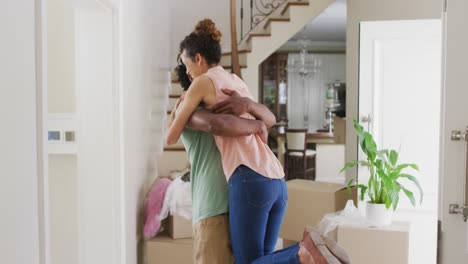 feliz pareja biracial abrazándose con alegría en la nueva casa