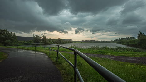 shot of dramatic sky with dark rain clouds above rural landscape along country road at daytime