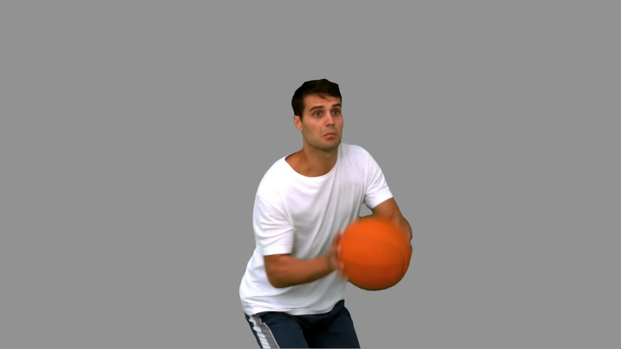 hombre guapo jugando con una pelota de baloncesto en la pantalla gris