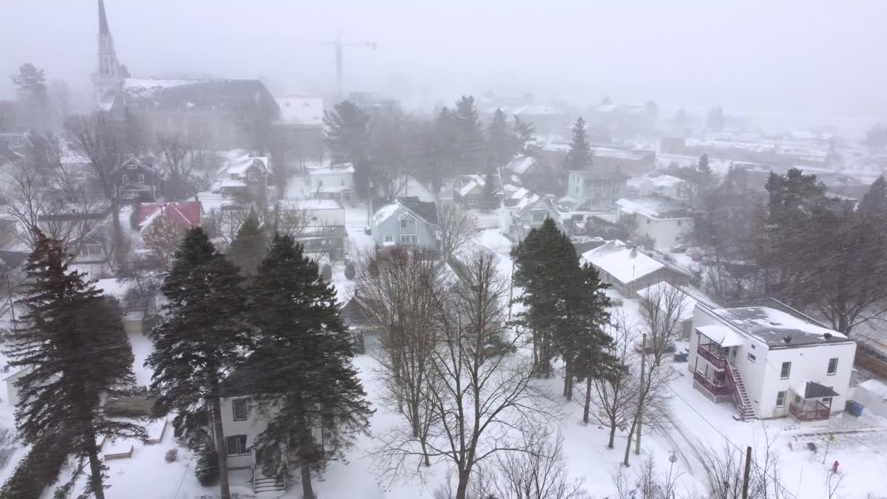 Snow-covered Orford town under a misty winter sky with trees and local buildings visible, Orford, Quebec, Canada.