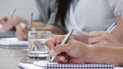 Close-up-of-hands-jotting-down-notes-at-a-conference