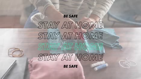 animation of words be safe stay at home over a person sewing coronavirus covid19  masks