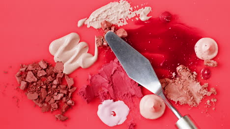 makeup palette and spatula on red surface
