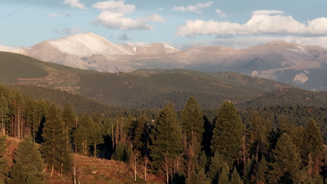 Ripresa cinematografica aerea con drone, effetto parallasse, prima neve sul picco 14er del Monte Blue Sky Evans a Denver, inizio autunno, splendida alba mattutina dorata e gialla, Montagne Rocciose del Colorado, movimento circolare lento verso destra