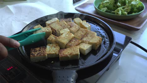 wide shot of tofu being cooked in pan special ingredients to cook a meal two cans of beans rice plantain avocado red onion and cilantro