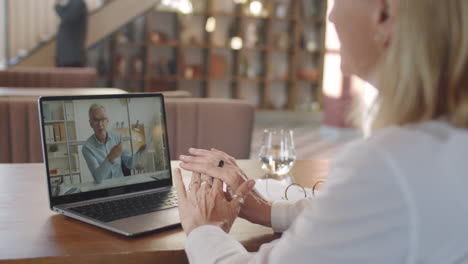 businesswoman speaking with senior coworker on web call in cafe