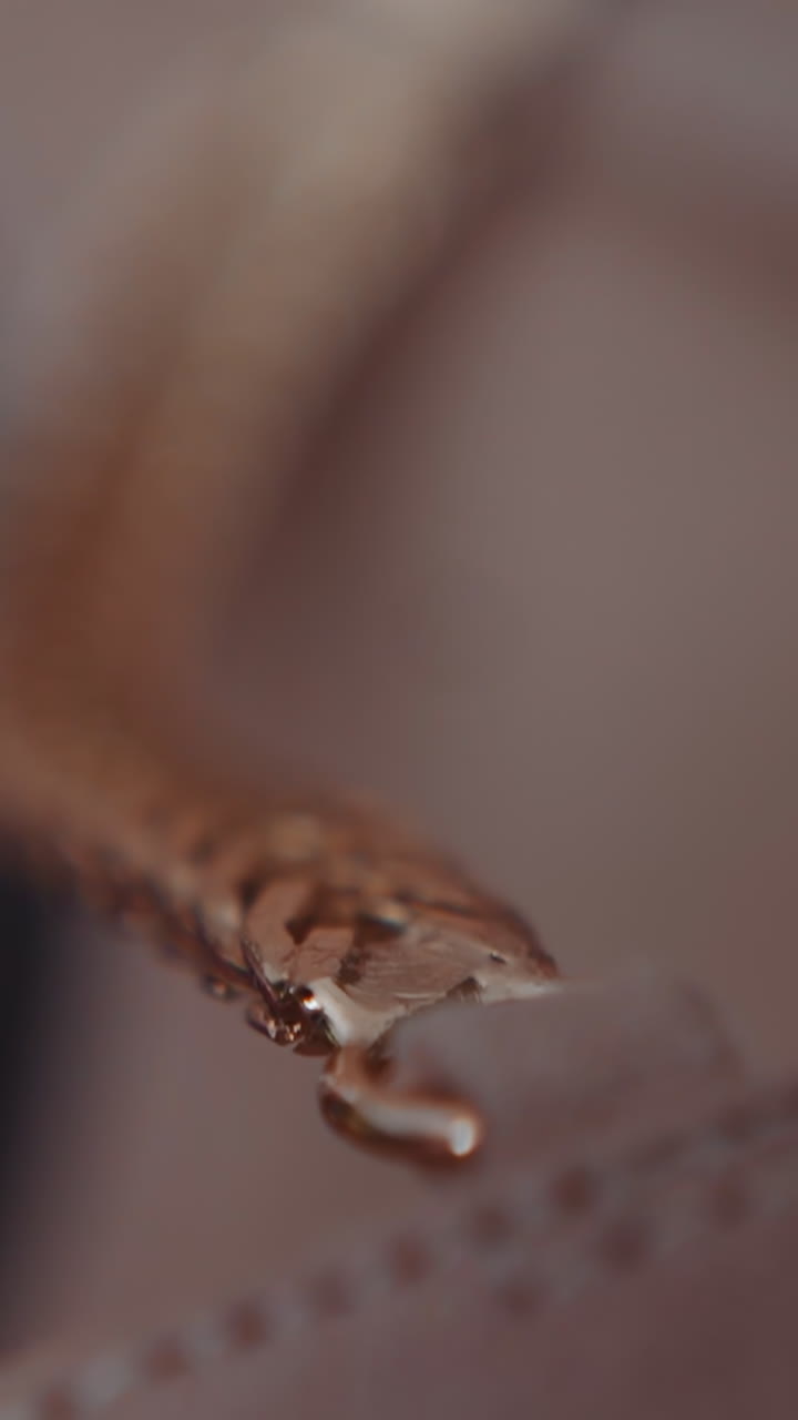 Golden chain fastened to leather clothes item edge on defocused background macro view. Elegant fashionable accessory. Glamorous items for women