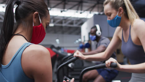 Entrenadora-Física-Femenina-Y-Cliente-Usando-Máscaras-Faciales-En-El-Gimnasio