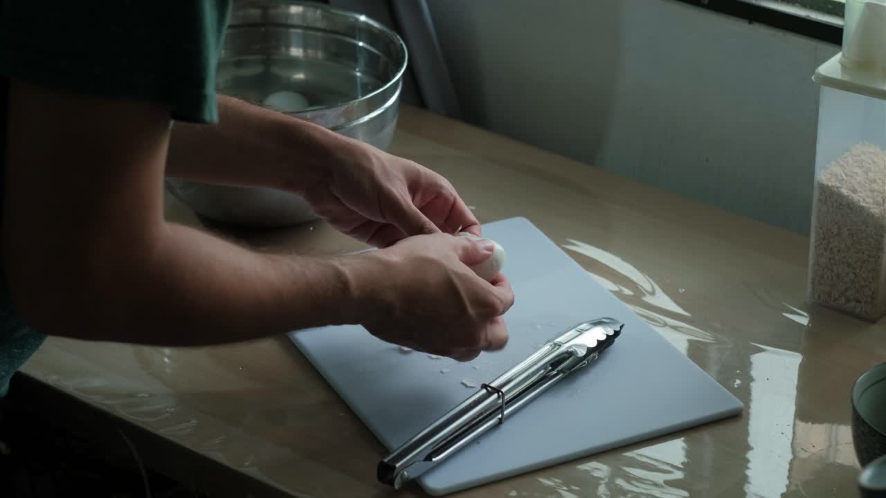 Cropped View Of A Person Removing Cooked Eggshells In A Kitchen. High Angle Shot