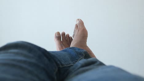 close up of a man's feet in blue jeans resting on a white surface