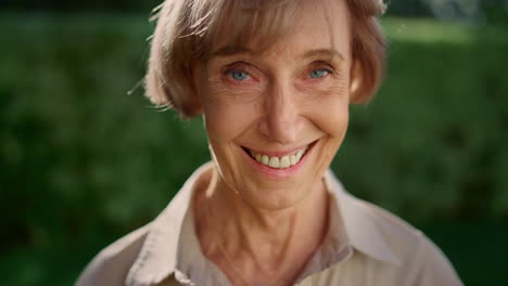 mature woman looking at camera. senior lady smiling in green park