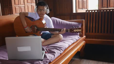 a boy plays guitar online at his home.