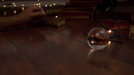 Several-candles-are-lit-on-the-table,-antique-books,-iron-pyramid-and-antique-books-are-visible