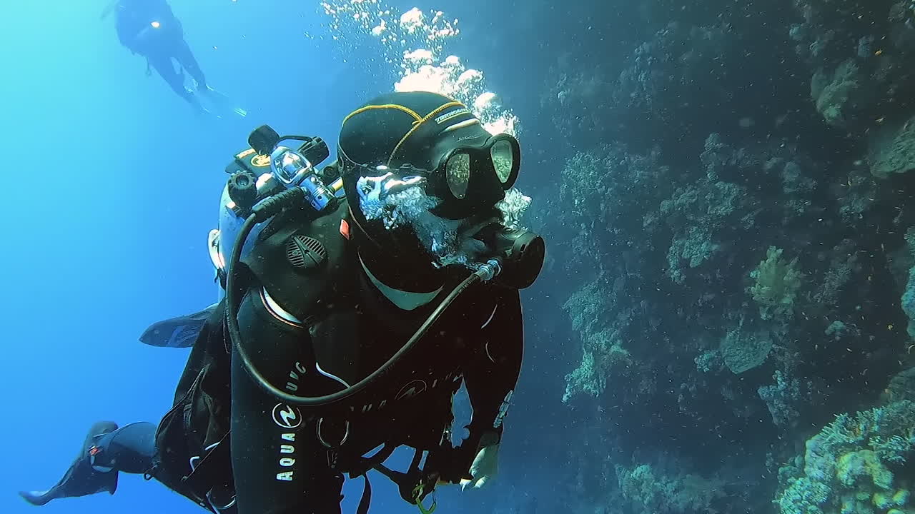 Scuba divers effortlessly swimming along a coral shelf along the great barrier reef new New Caledonia