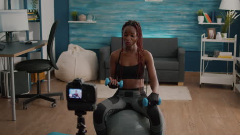 black woman trainer practicing morning yoga exercise sitting on fitness swiss ball