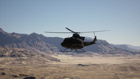 a military helicopter flying over a desert