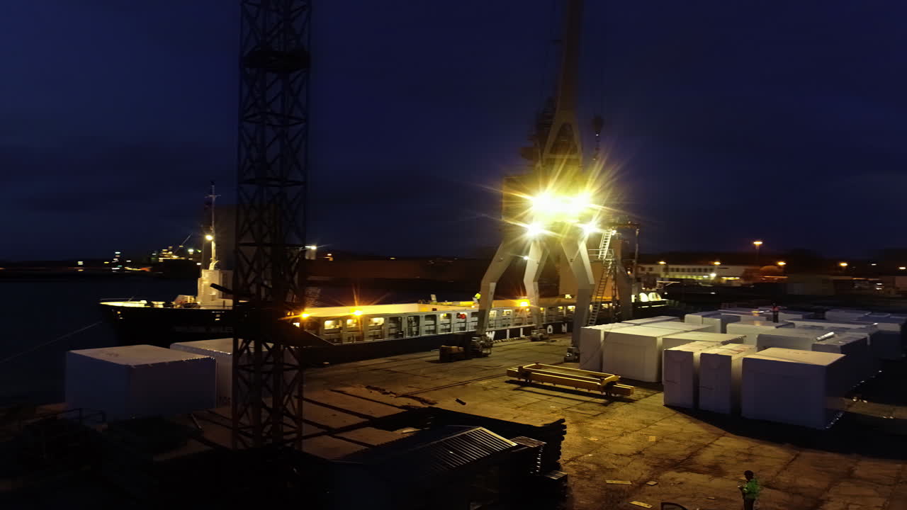 trabajadores que trabajan de noche con una grúa en un buque de carga en un puerto