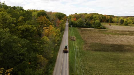 Aerial-view-of-a-tractor-pulling-a-trailer-through-the-rural-countryside