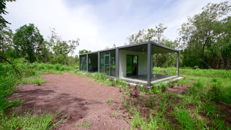 camino de grava de tierra tropical no desarrollada a la casa de estilo caja de contenedor rectangular desmontable en la selva del bosque tropical