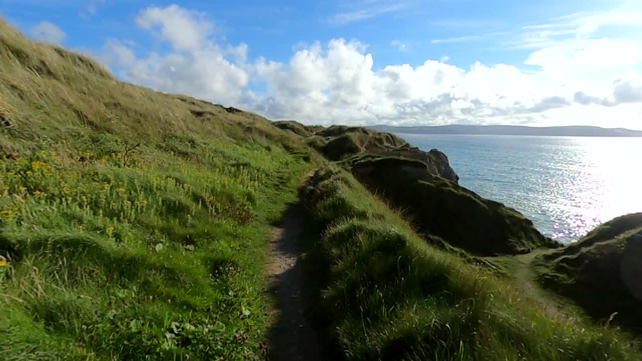 caminando por un sendero costero con vistas al océano en un día soleado