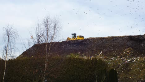 Stack-of-different-types-of-large-garbage-dump,-plastic-bags,-and-landfill-full-of-trash,-environmental-pollution,-truck-dump-waste-products-polluting-in-a-dump,-seagulls-in-the-sky,-distant-wide-shot