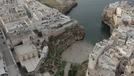 Aerial-circle-view-of-beach-embedded-in-the-city-with-people-swimming-in-crystal-sea