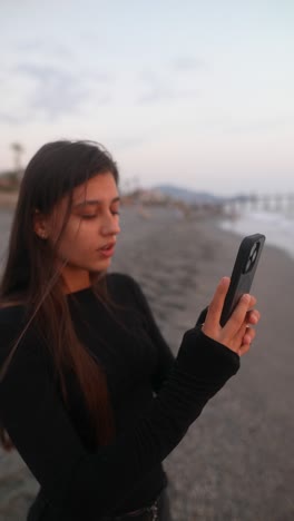 teenage girl taking photo on beach at sunset