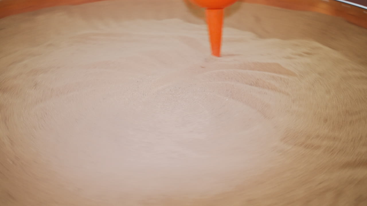 The pendulum draws on the sand. Science exhibition museum.