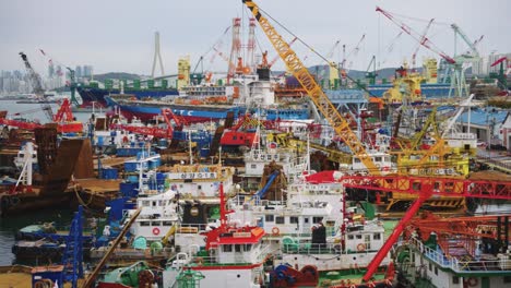 grúas y barcos de pesca en el puerto de busan en corea del sur en un día nublado
