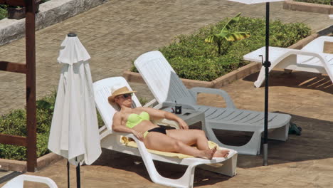 beautiful young women relaxing on the deck chair near the pool