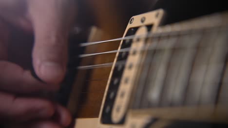 extreme close up of right hand picking electric guitar