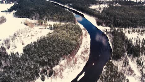un río sinuoso cerca de un pequeño pueblo con un macizo forestal