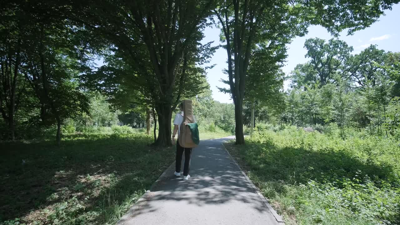 숲 근처의 거리에서 기타를 들고 는 젊은 남자