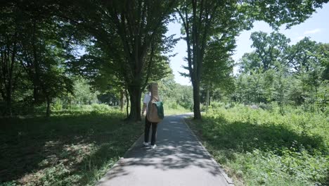 young man walking with guitar on street near forest