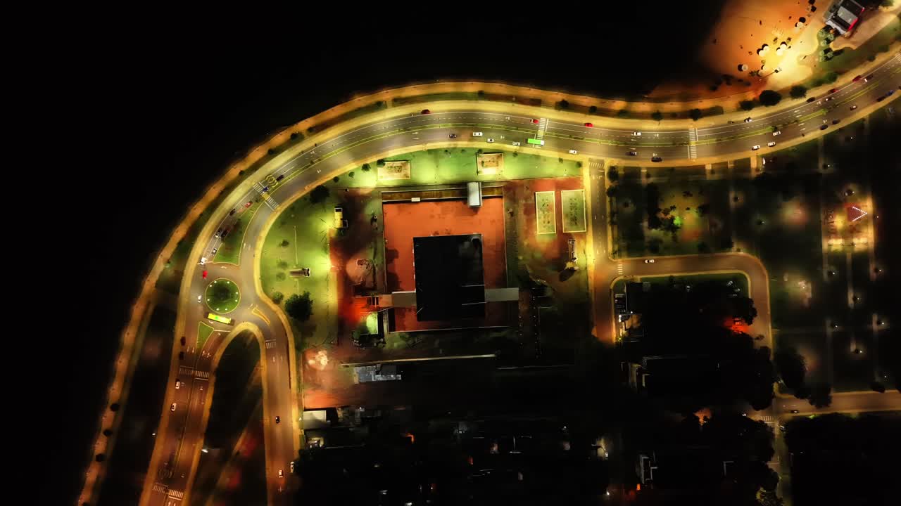 Top-down aerial movement of iconic Costanera's Roundabout with urban lights at night in Posadas, Misiones, Argentina.