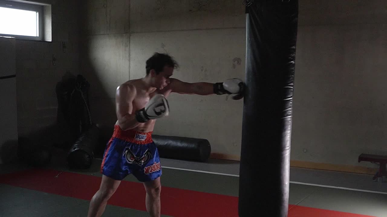 체육관에서 권투 가방에 강한 공격적인 펀치를 던지는 백인 복서