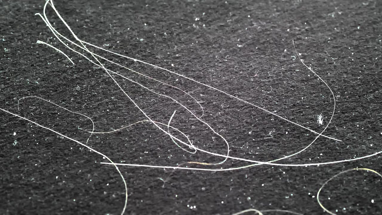 Close-up of Human Hair and Dust Particles on Dark Fabric