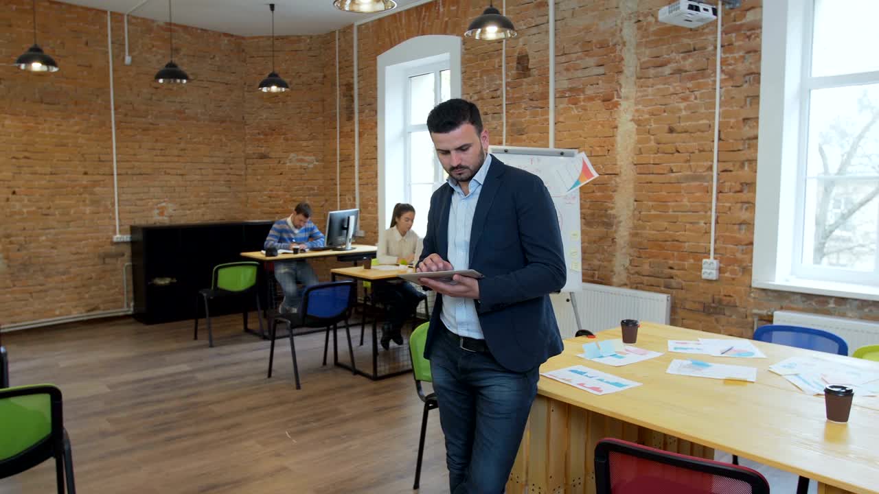 Hombre usando una tablet negra con pantalla verde en una oficina moderna. Toma con estabilizador de cámara
