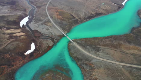 car crossing bridge over the beautiful flowing emerald glacier river hvita in highlands, iceland - aerial drone shot