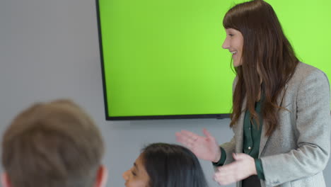 glückliche geschäftsfrau, die kollegen mit green-screen-tv eine präsentation gibt