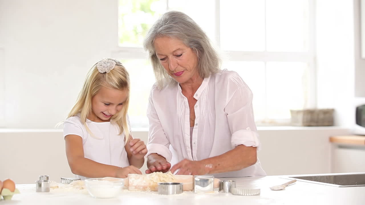 Bambina che stende la pasta con la nonna