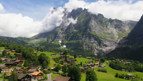 cinematic drone shot flying over buildings in grindelwald, in switzerland’s bernese alps