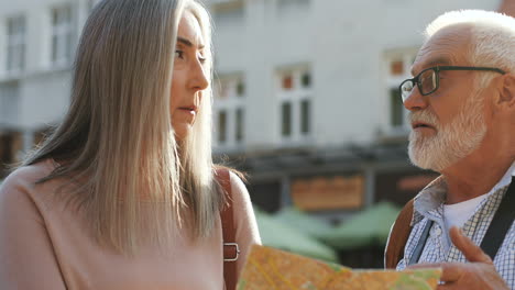 close up of senior couple standing outdoors with a map and deciding which way to take