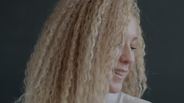 Portret van een glimlachende vrouw met krullend blond haar