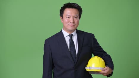 mature japanese businessman against green background