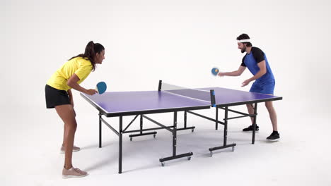 playing table tennis, man and woman enjoying game in studio setting
