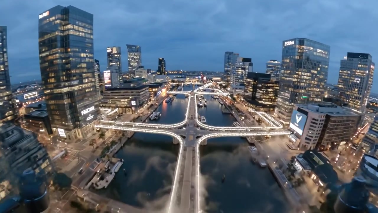 Vista aérea de un paisaje urbano moderno con puentes y reflejos al anochecer, con luces vibrantes que iluminan el entorno urbano